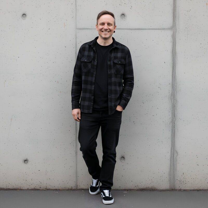 Björn Fischer, Gründer der Herzwerk-Academy, lächelnd vor einer Betonwand